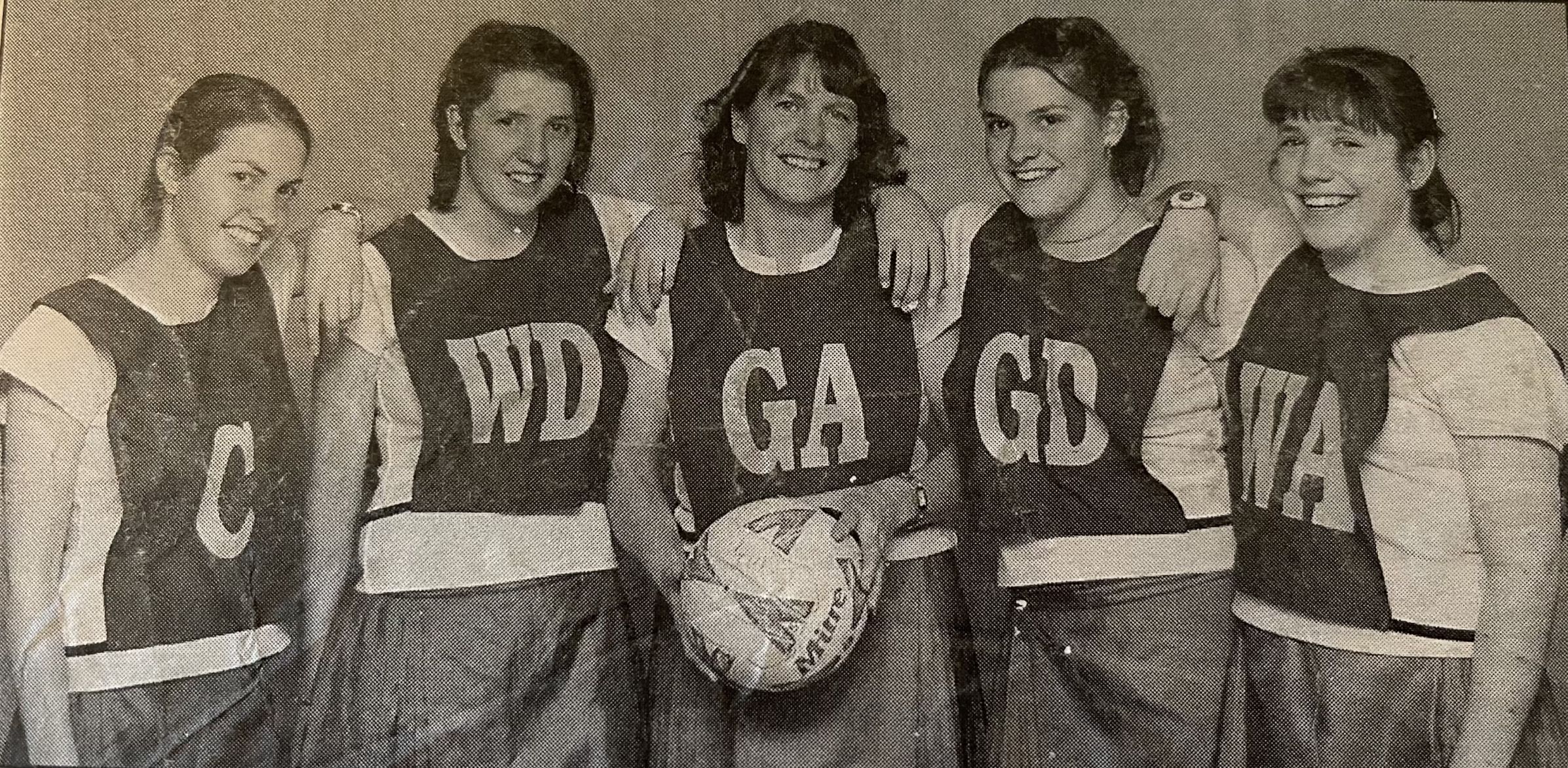 A photos of a newspaper image of five women wearing netball bibs.