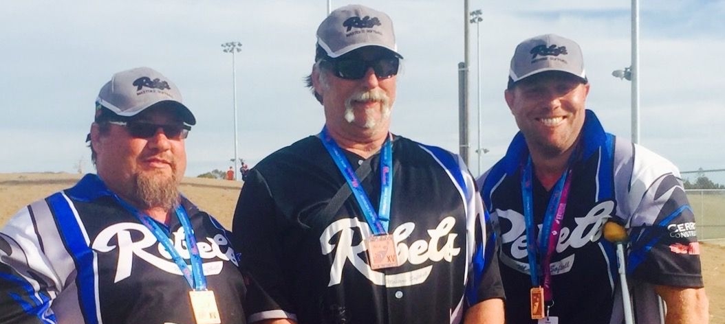 Three men stand together, wearing baseball shirts and caps.